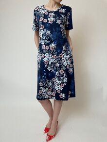 Дамска рокля от памучно жарсе, разкроен модел с къс ръкав, дължина около коляното, два странична джоба десен тъмно синьо на розови цветенца